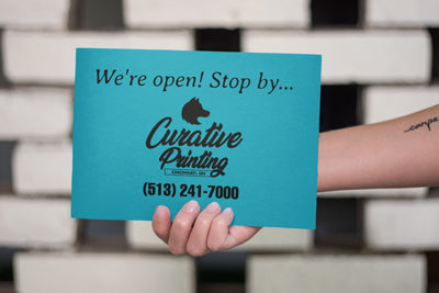 Arm of a female holding a postcard from the mail representing Curative's Every Door Direct Mail (EDDM) Services