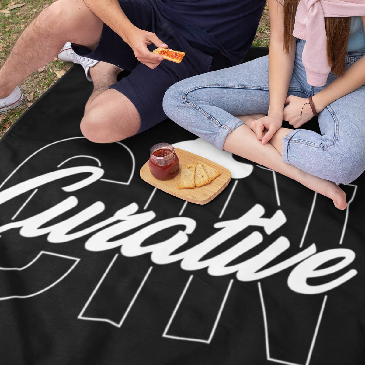 Couple picnicking on a black custom promotional throw blankets by curative printing