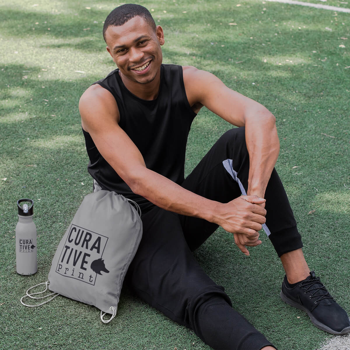 Man sitting with grey custom promotional drawstring bags by curative printing