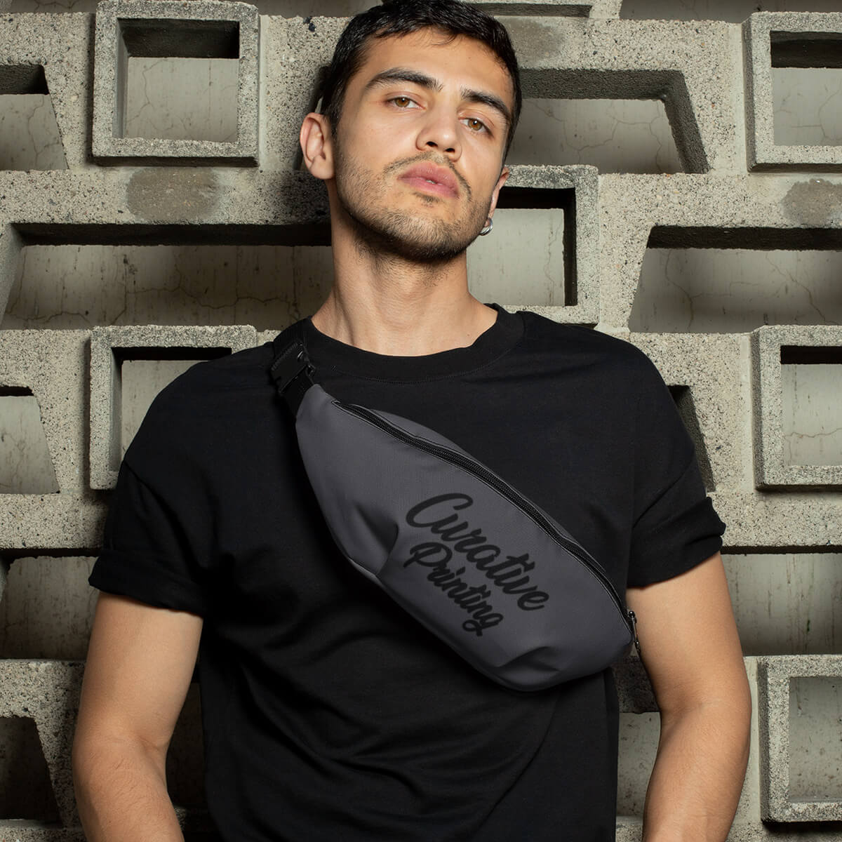 Man against brick wall with grey custom promotional fanny pack bags by curative printing