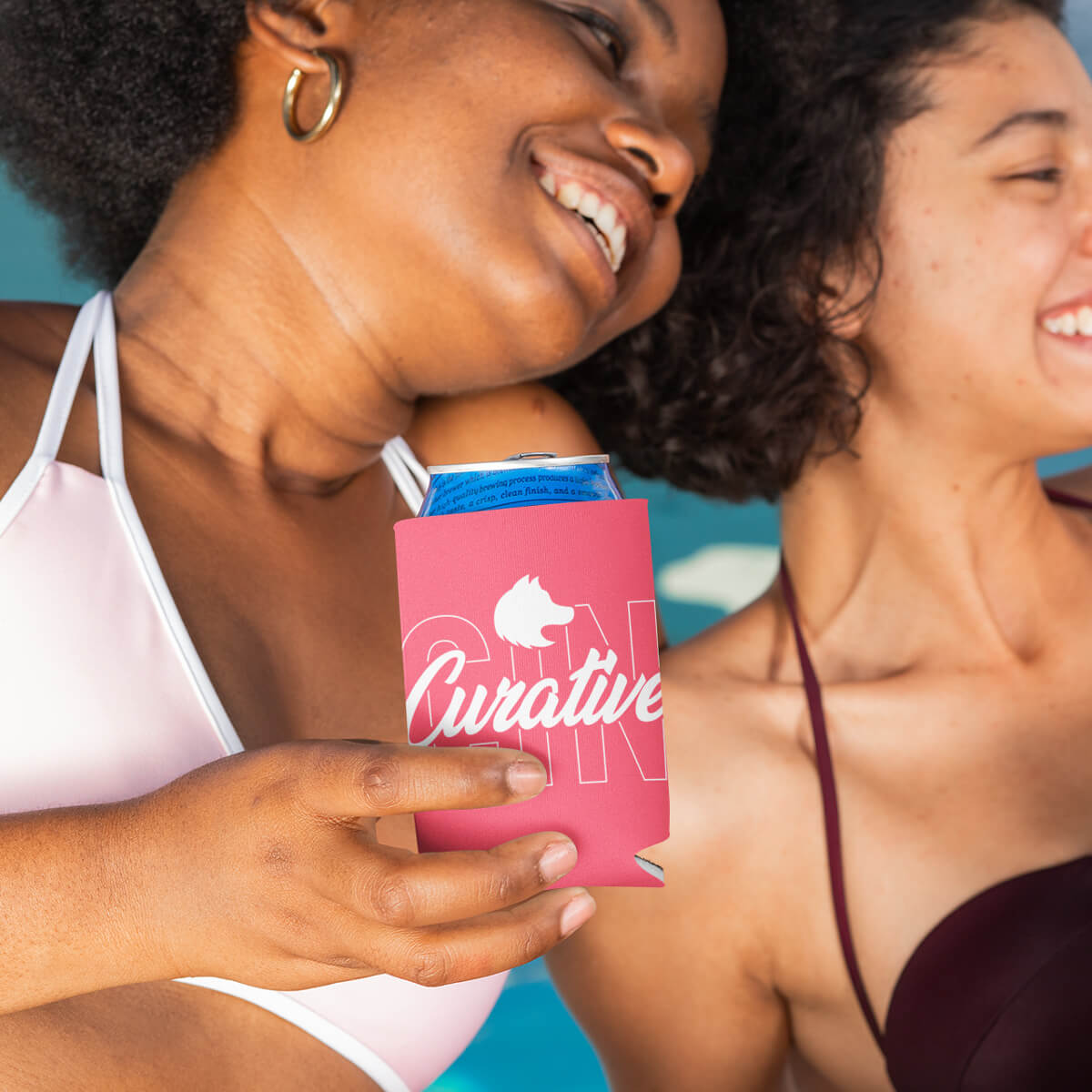 Women poolside drinking from pink can cooler custom promotional drinkware by curative printing