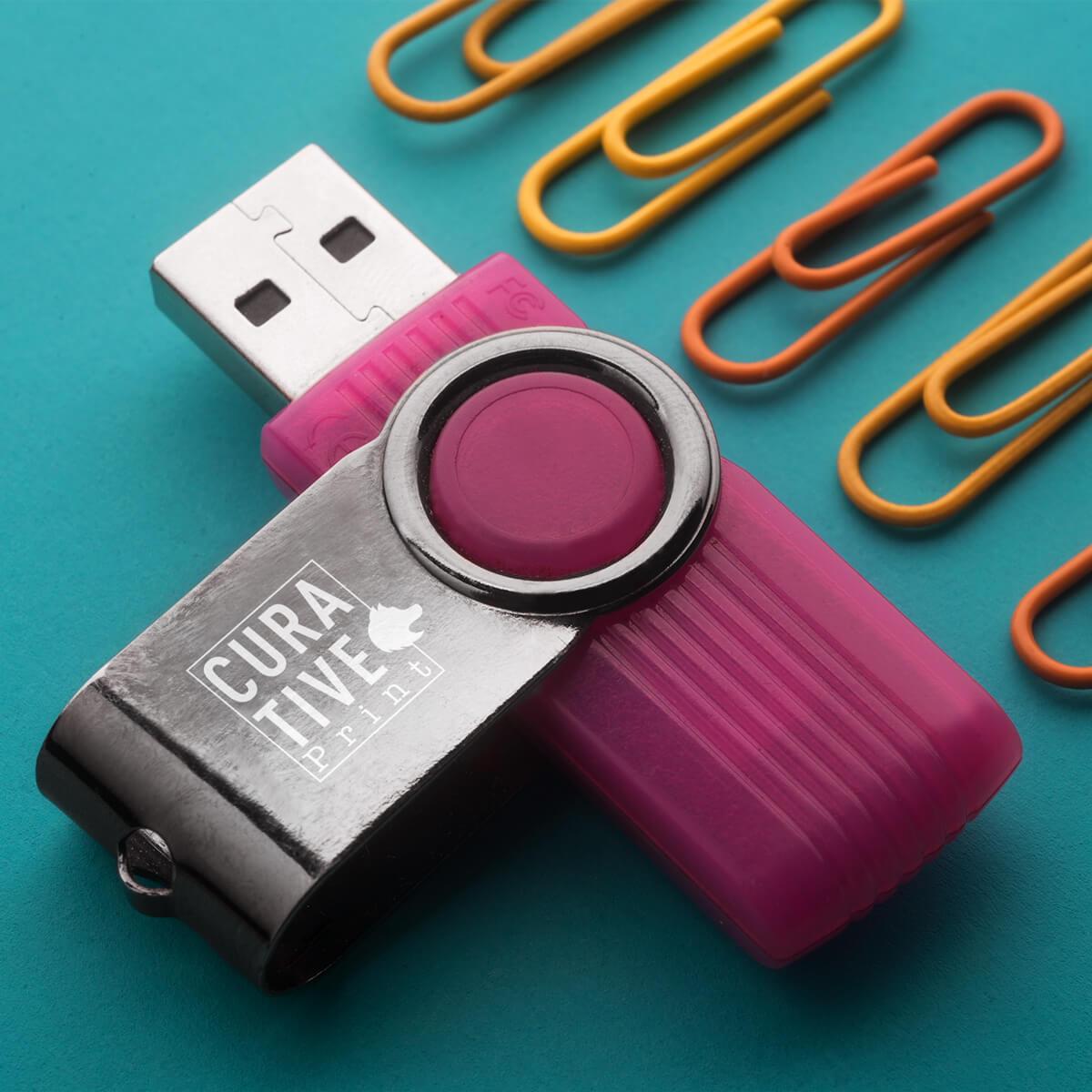 Paper clips laying next to a purple USB flash drive promotional technology by curative printing