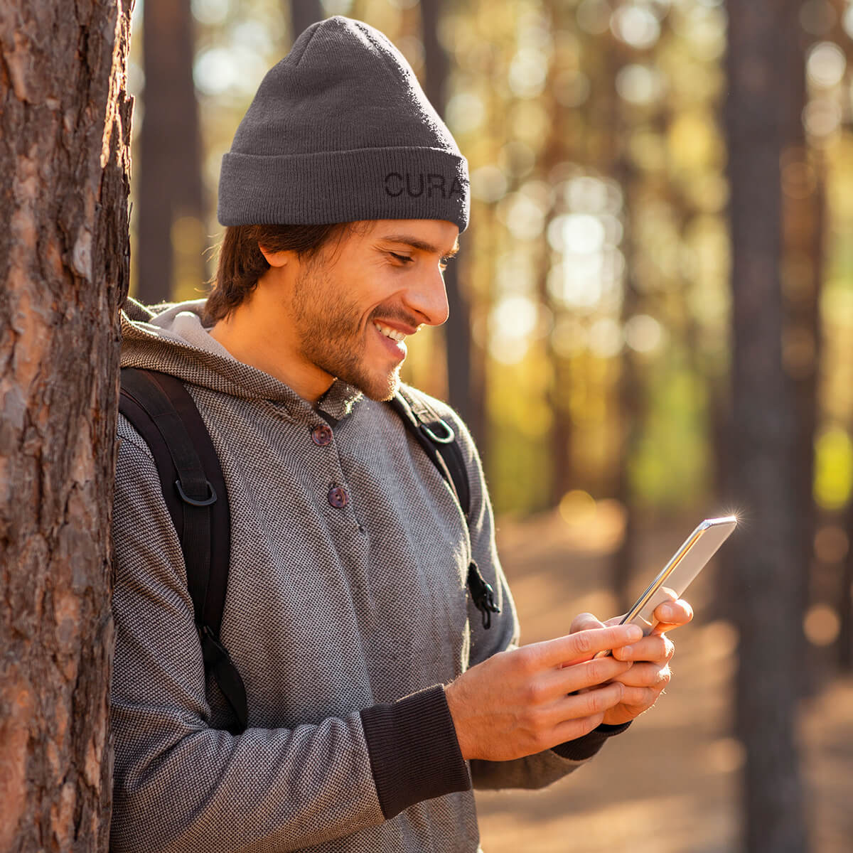 Outdoorsman wearing dark grey beanie with Curative Printing logo while texting
