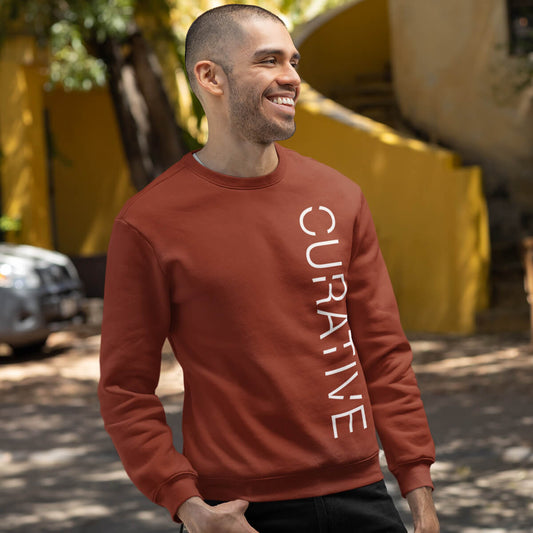 Man stands outside wearing red Curative crewneck sweatshirt