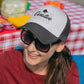 Woman at a picnic wearing grey trucker hat with black curative printing logo imprint