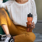 Woman sitting with orange sports bottle custom promotional drinkware by curative printing