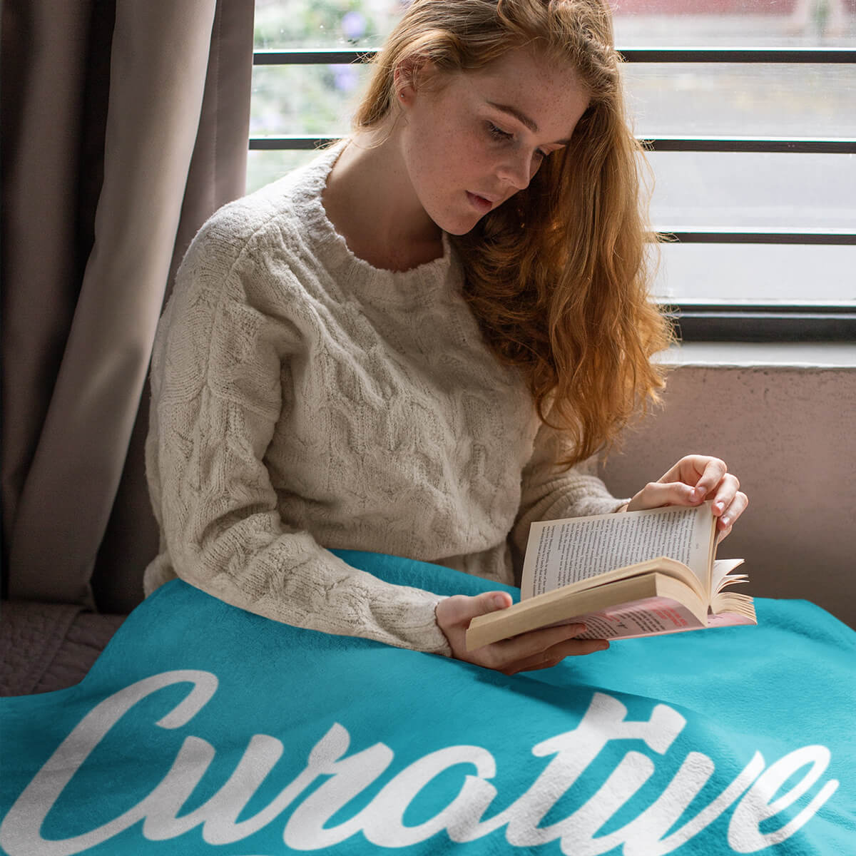 Woman reading in a turquoise custom promotional throw blankets by curative printing