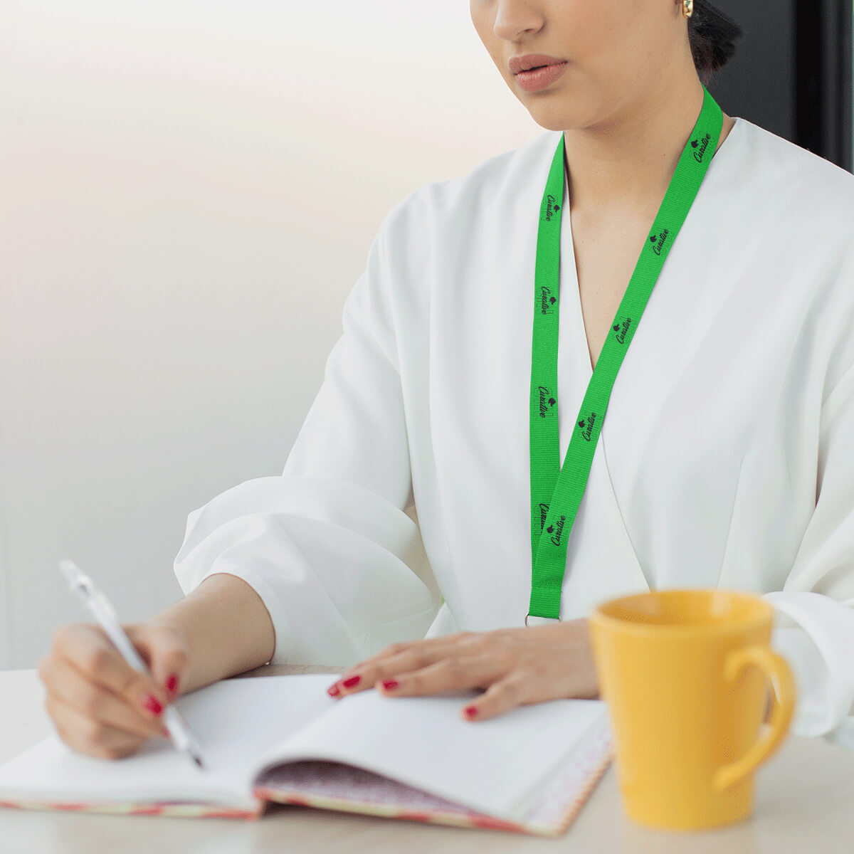 Woman taking notes wearing lime with black imprint lanyard promotional wellness & safety by curative printing