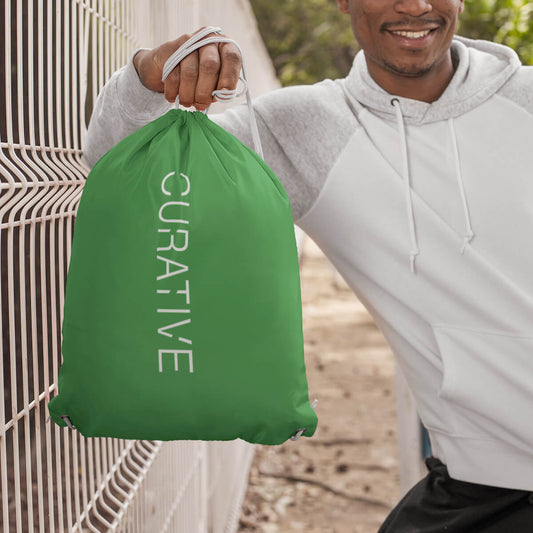 Man leaning with green custom promotional drawstring bags by curative printing
