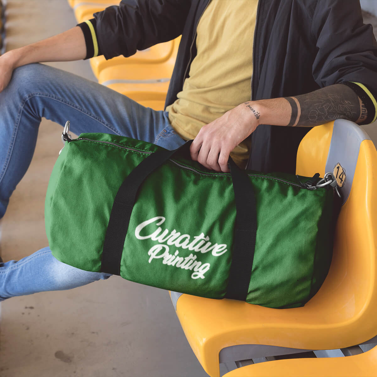 Man sitting by green custom promotional duffle bags by curative printing