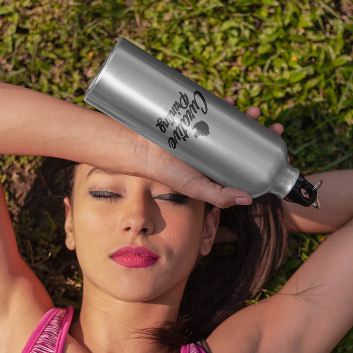 Woman relaxing on grass with silver sports bottle custom promotional drinkware by curative printing
