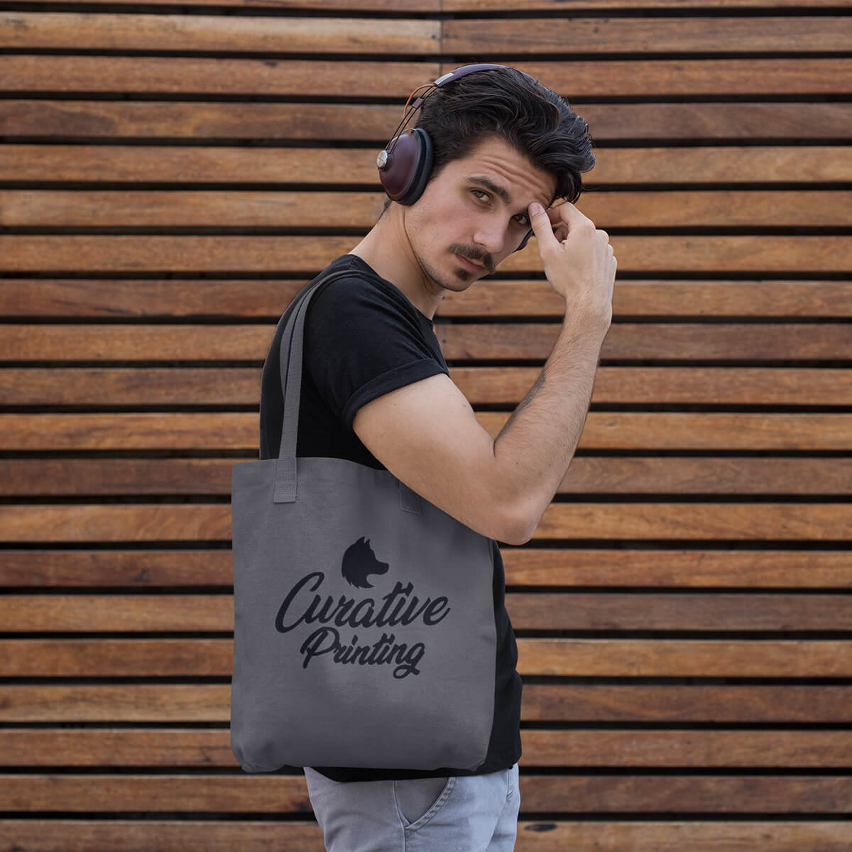 Guy carrying grey with black imprint custom promotional tote bags by curative printing