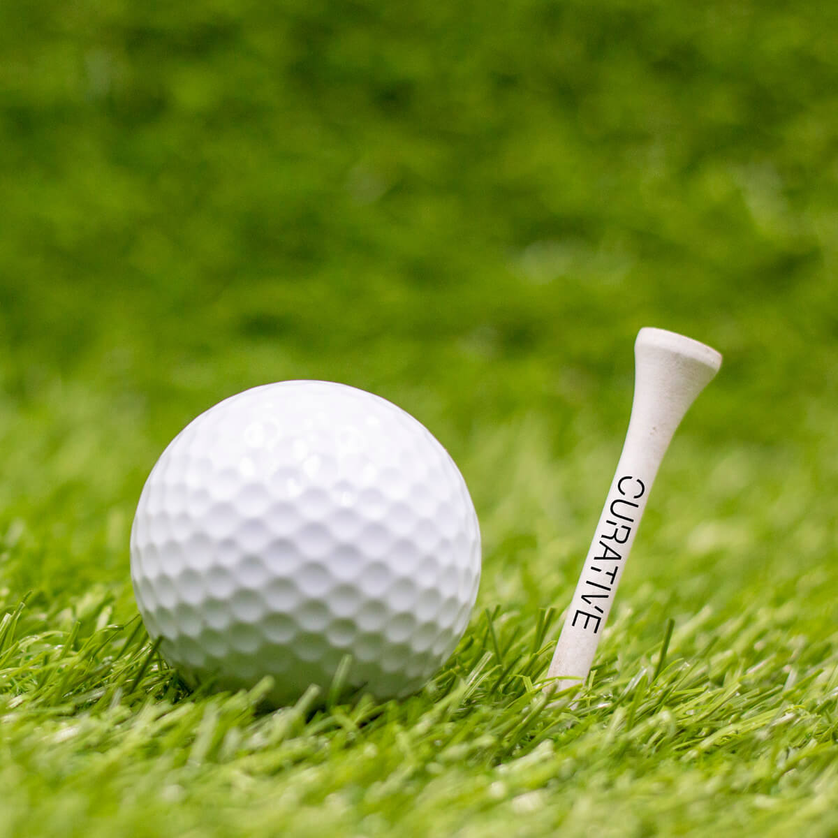 Golf ball beside white logo'd golf tee custom promotional golf by curative printing
