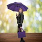Woman holding purple auto open umbrella and purple tote bag.