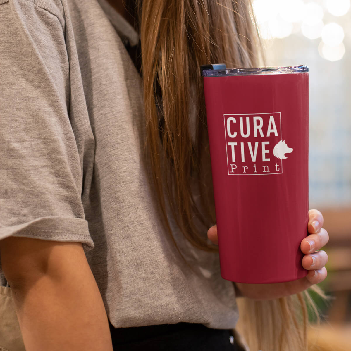 Woman holding red travel mug tumbler custom promotional drinkware by curative printing
