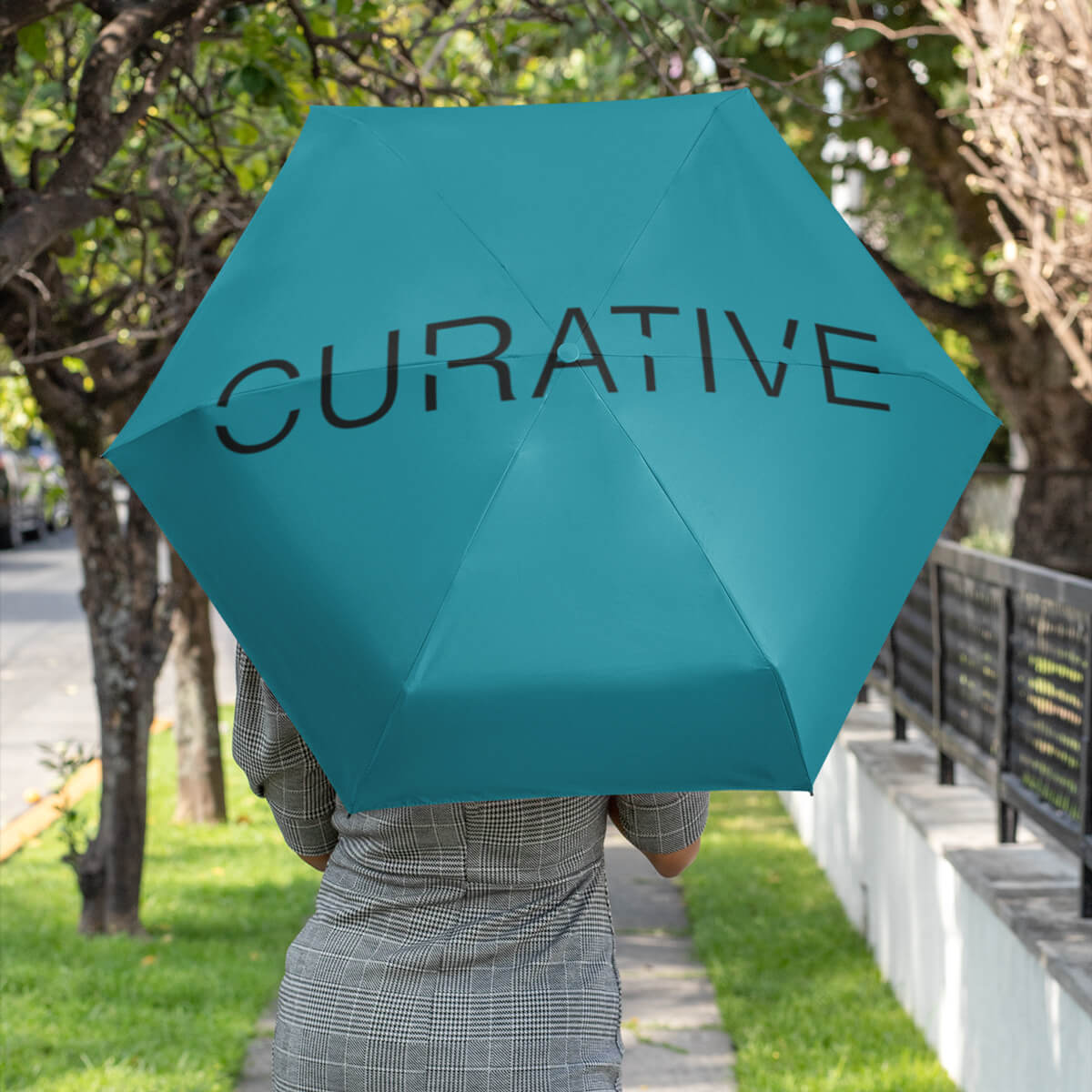 Woman walking away holding turquoise folding umbrella promotional umbrellas by curative printing