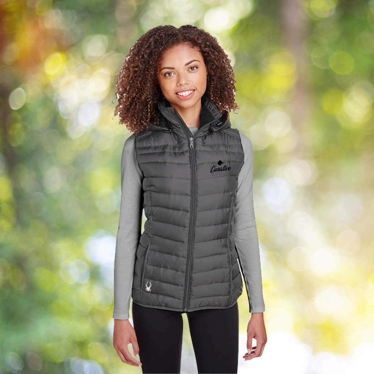 Woman outdoors wearing grey vest outerwear apparel with black curative printing logo imprint